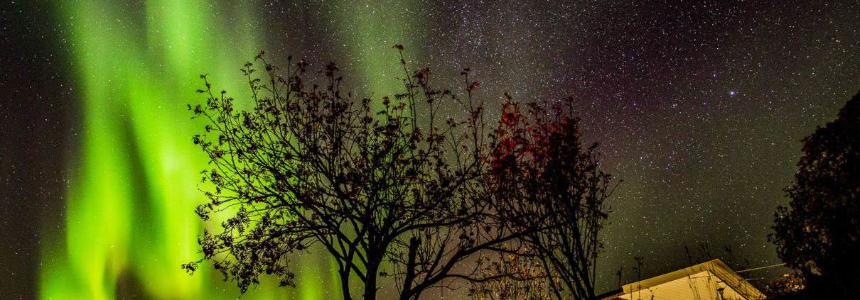 Nordlys og stjernehimmel over bebyggelse